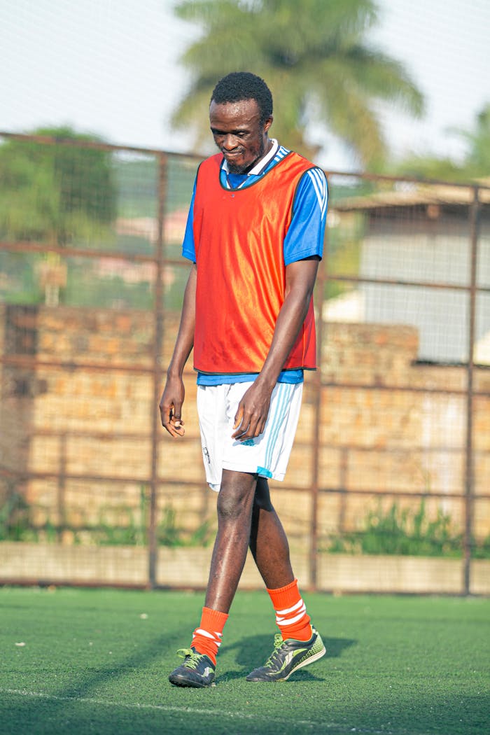 our-services-1 A young athlete in a football uniform walking on an outdoor field during practice.