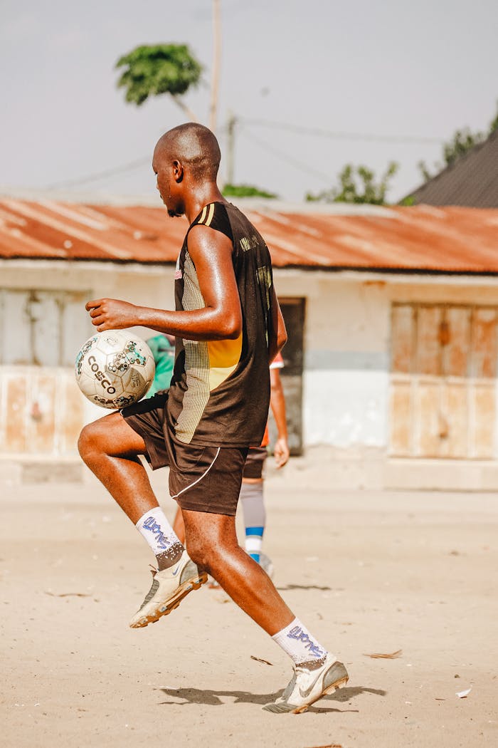 our-services-3 A young man skillfully playing soccer on a sandy outdoor field under clear skies.